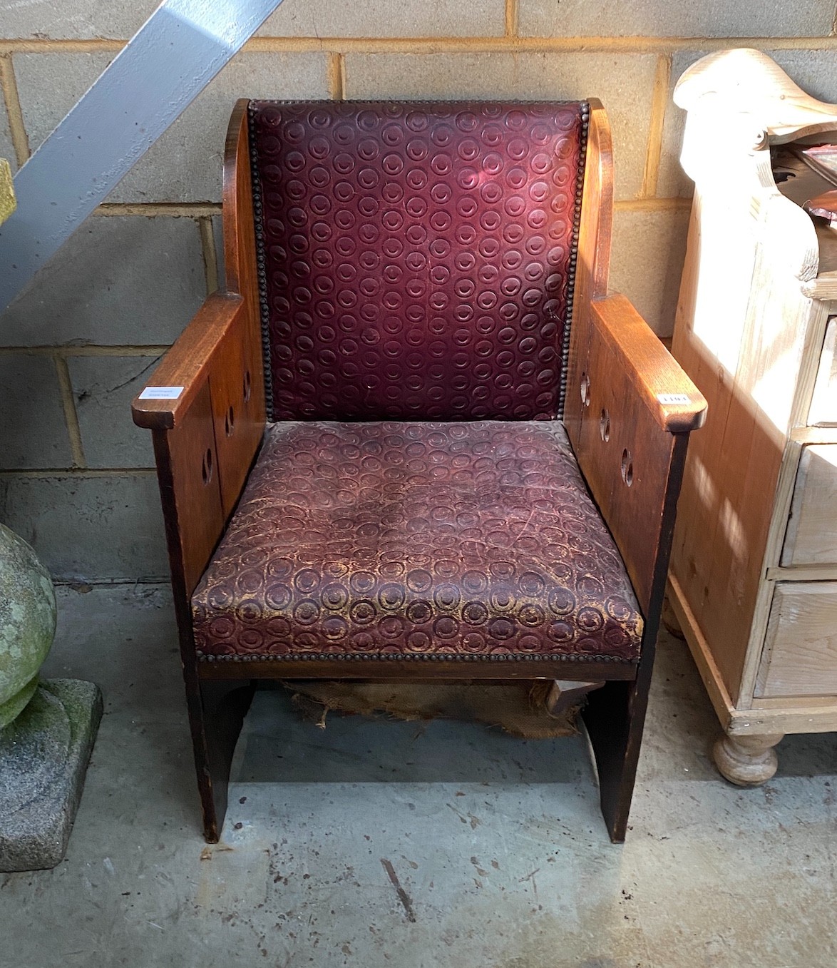 An early 20th century Arts & Crafts oak armchair, with pierced sides and embossed leather seat and back, width 60cm, depth 59cm, height 86cm